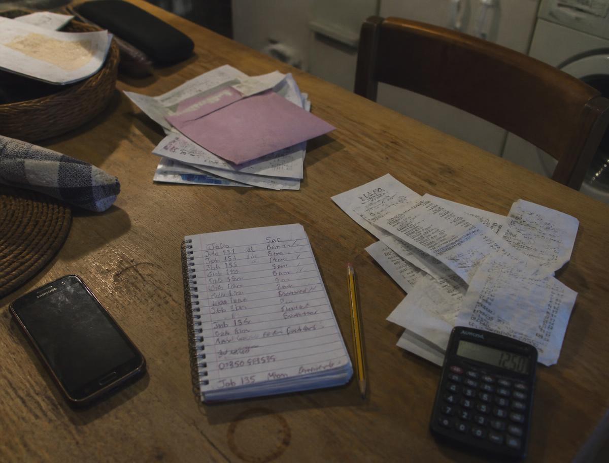 Receipts, a notebook and a calculator spread over a kitchen table